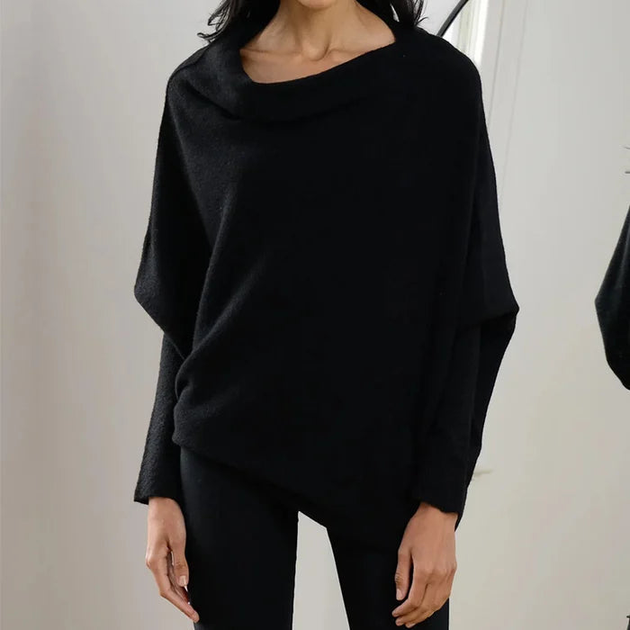 Modell bär en modern draperad asymmetrisk damtröja, visar dess stilrena passform och mångsidighet.