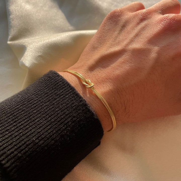 Detaljerat damarmband med symbolisk kärleksknop. Justerbart smycke, minimalistisk och chic design.
