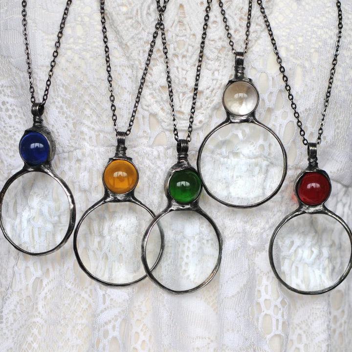 "Elegant kvinnligt hänge halsband med förstoringsglas i unikt design, finns i gul, röd, grön, blå, transparent."