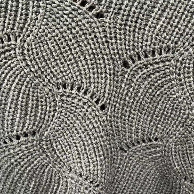 "Elegant långstickad damponcho med fladdermusärmar, ger stil och värme, i mjuk grå ton."
