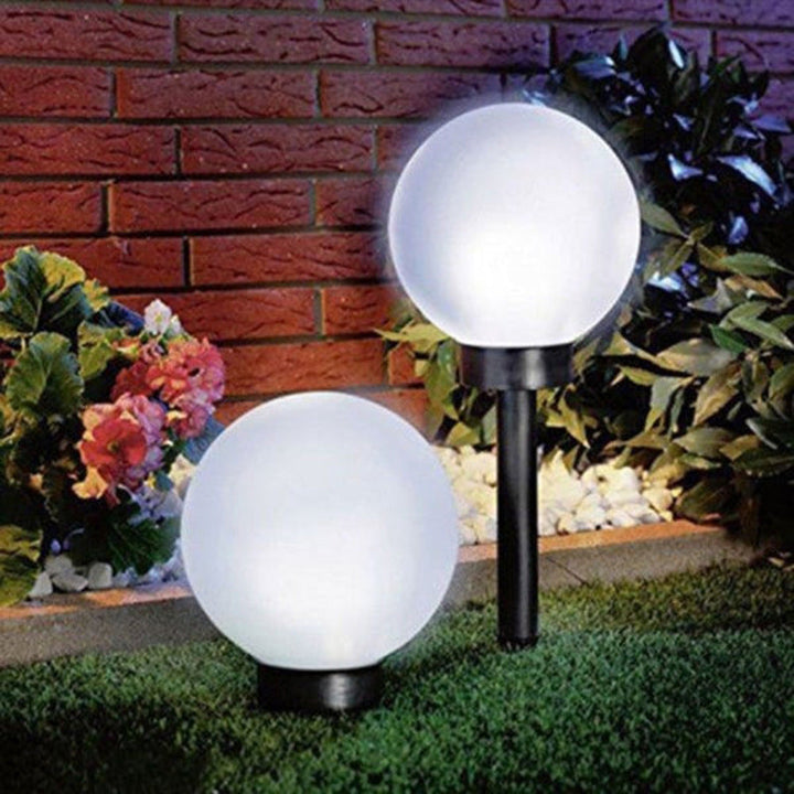 "Elegant LED-solcellslampa för gräsmatta med kulvit design, silverdetaljer och varm belysning för trädgårdar."