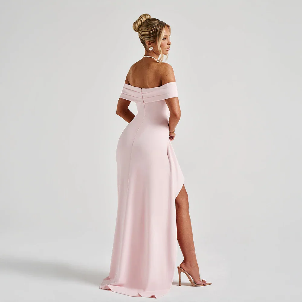 Kvinna poserar i elegant off shoulder maxiklänning med slits, en modern festklänning för dam.