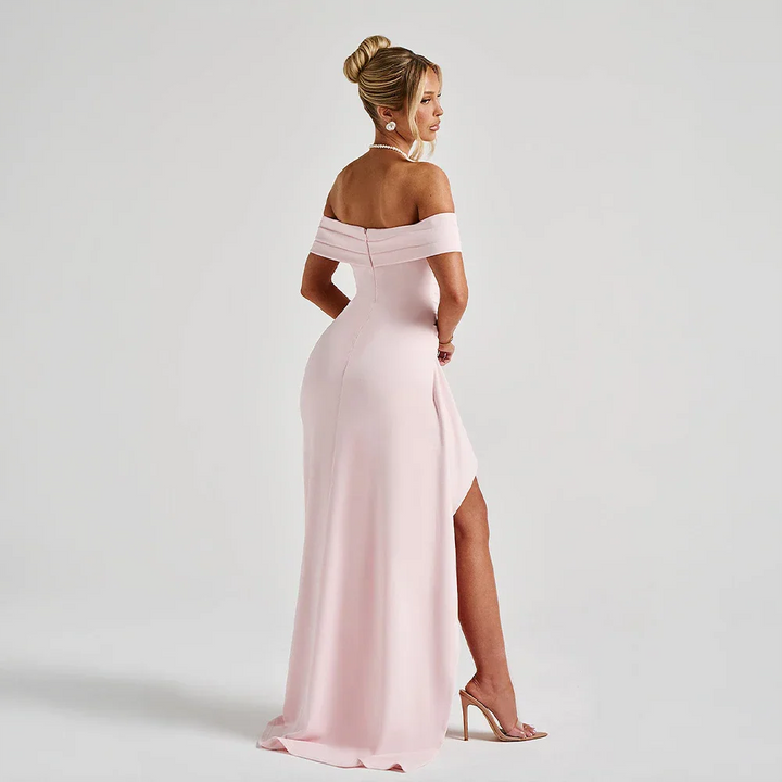 Kvinna poserar i elegant off shoulder maxiklänning med slits, en modern festklänning för dam.