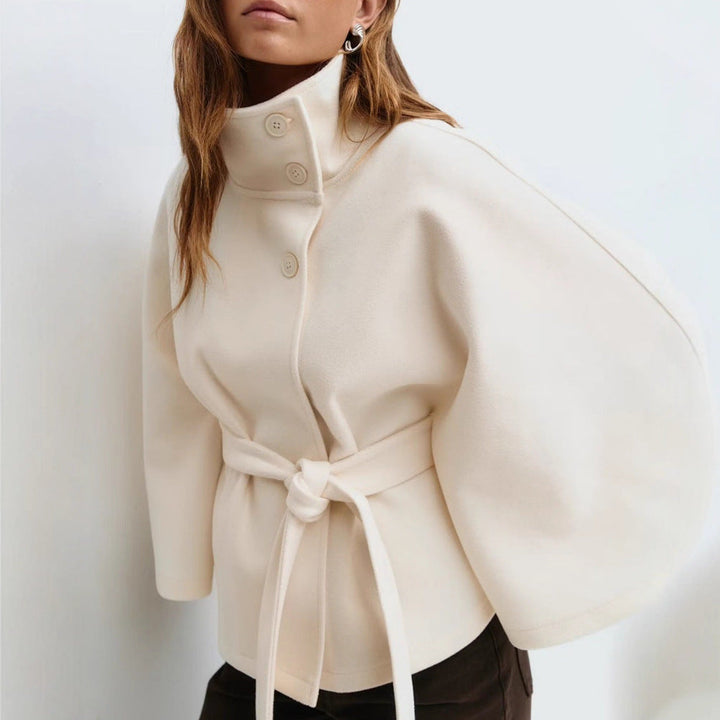 Kvinnlig modell bär en elegant omlottjacka med ståkrage och vida ärmar, helkroppsbild utomhus