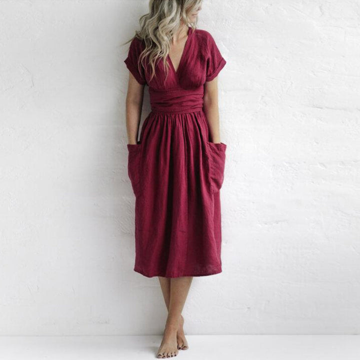 "Elegant rosa damklänning med hög midja, V-ringning, korta ärmar och fickor, perfekt för stilfulla tillfällen."