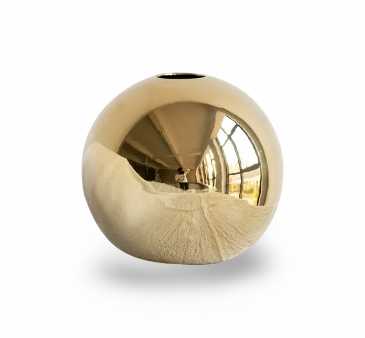 Elegant rund gyllene keramikvas fotograferad från sidan, visar den vackra silhuetten och moderna designen.