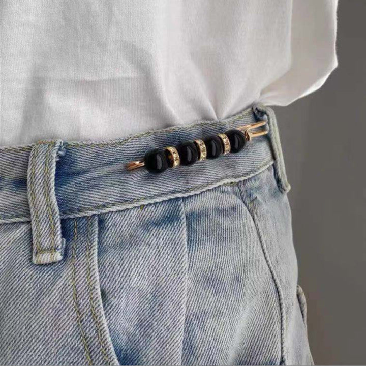 "Elegant säkerhetsnålsbrosch med vita pärlor och strass, perfekt för damkläder, i svart och vitt för stil och matchning."