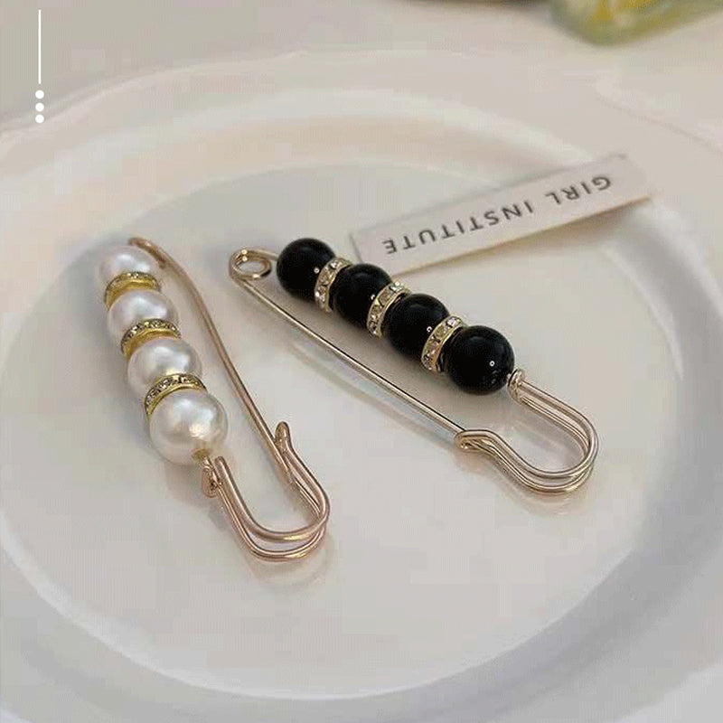 "Elegant säkerhetsnålsbrosch med vita pärlor och strass, perfekt för damkläder, i svart och vitt för stil och matchning."