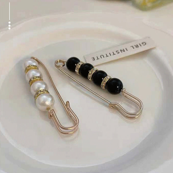 "Elegant säkerhetsnålsbrosch med vita pärlor och strass, perfekt för damkläder, i svart och vitt för stil och matchning."