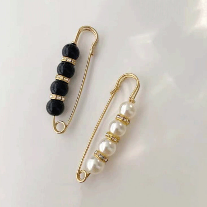 "Elegant säkerhetsnålsbrosch med vita pärlor och strass, perfekt för damkläder, i svart och vitt för stil och matchning."