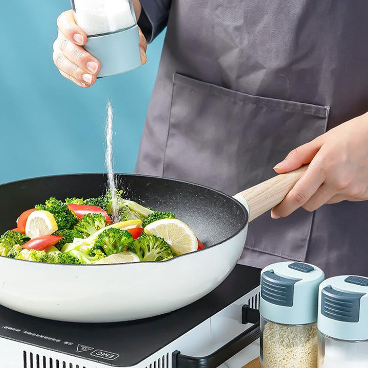 "Elegant saltkar i glas med mätfunktion, böjd form och modernt lock, perfekt för kryddförvaring i köket."