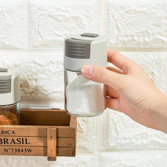"Elegant saltkar i glas med mätfunktion, böjd form och modernt lock, perfekt för kryddförvaring i köket."