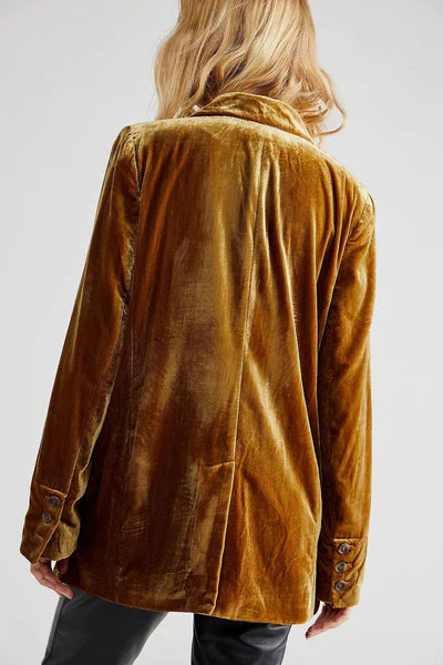 Närbild på tyget och textur av en beige långärmad damkavaj med fin knappslå, för en elegant look.