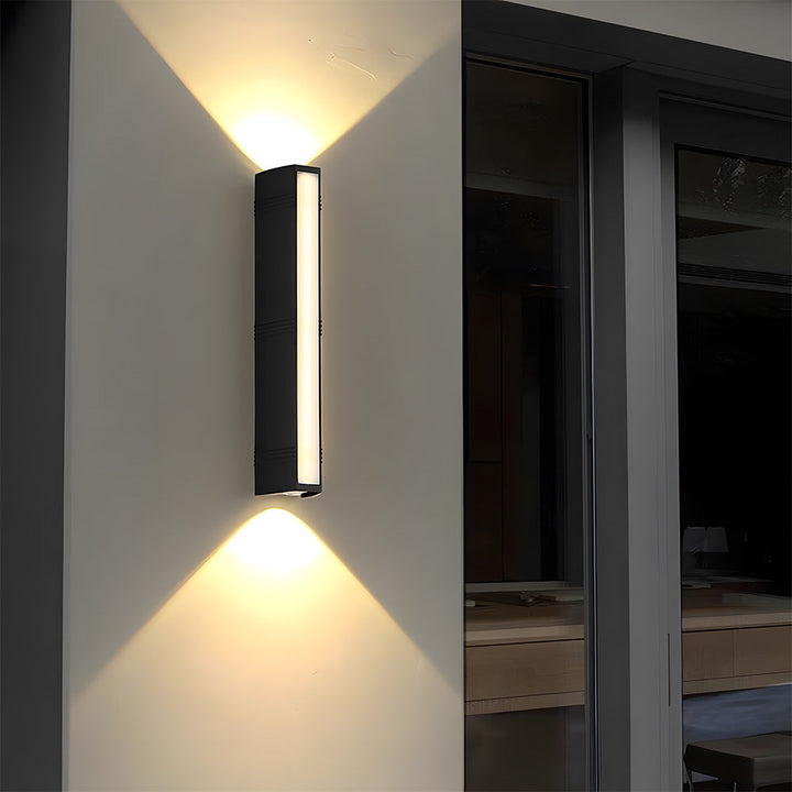 Modern svart vägglampa med upp/ner-ljus, idealisk för utomhusmiljöer.