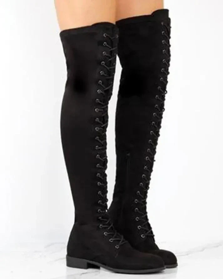 Detaljbild av svarta kvinnors knähöga snörstövlar, visar snörning och material för en tidlös och mångsidig look.