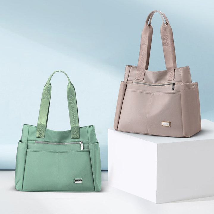 "Elegant vattentät damkurirväska i Oxfordnylon, stilren design, champagnefärgad, perfekt för dagliga utflykter."