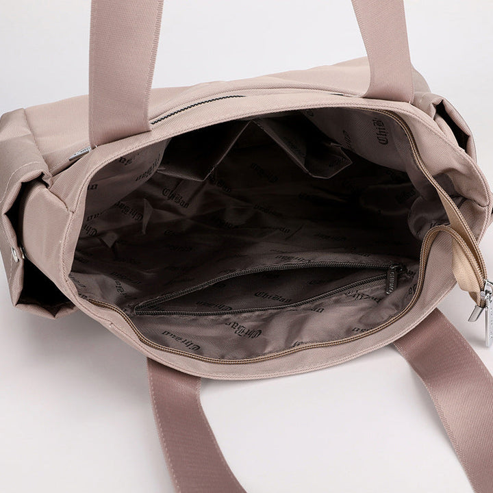 "Elegant vattentät damkurirväska i Oxfordnylon, stilren design, champagnefärgad, perfekt för dagliga utflykter."