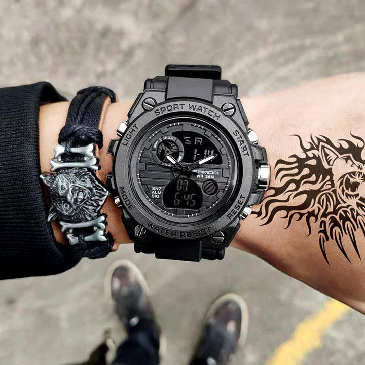 "Elektronisk dubbeltskärmsklocka, svart och armégrön, med silver och guld detaljer, för utomhusbruk och tidszonssynk."