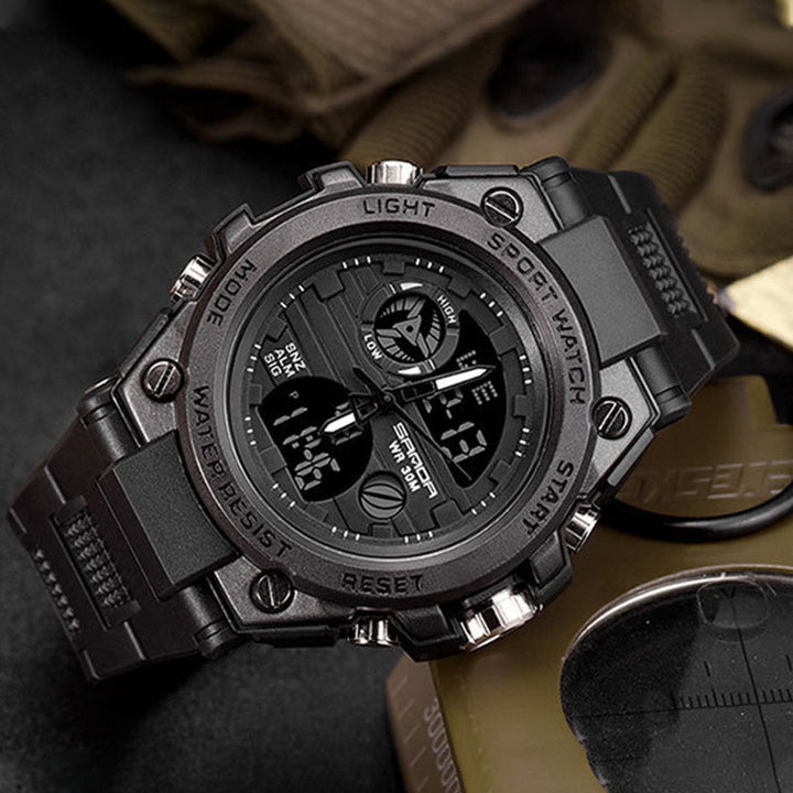 "Elektronisk dubbeltskärmsklocka, svart och armégrön, med silver och guld detaljer, för utomhusbruk och tidszonssynk."