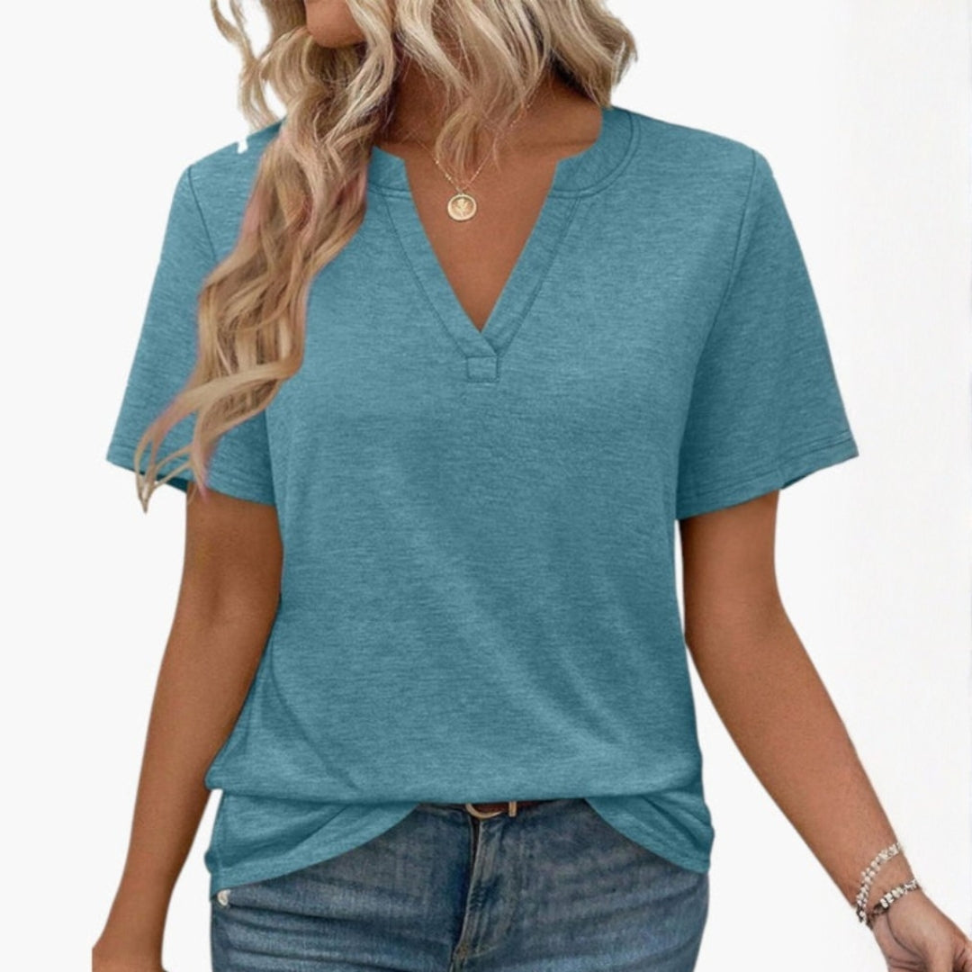 Närbild på tyget av en enfärgad dam-T-shirt med V-ringning, framhävande dess mjuka kvalitet och design.