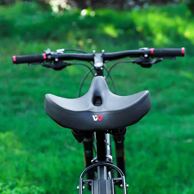 Ergonomisk bred cykelsadel i svart konstläder med andningsfunktion och tjock vaddering för maximal komfort.