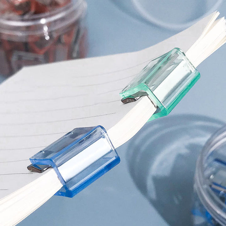 "Färgglada metallpappersklämmor i grönt, gult, lila, rosa, transparent och blått, perfekt för kontor och skola."