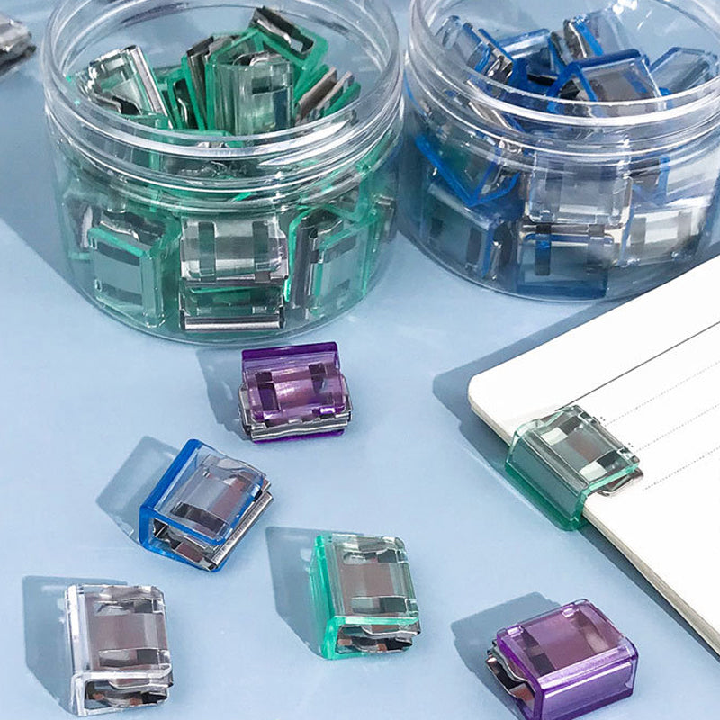 "Färgglada metallpappersklämmor i grönt, gult, lila, rosa, transparent och blått, perfekt för kontor och skola."