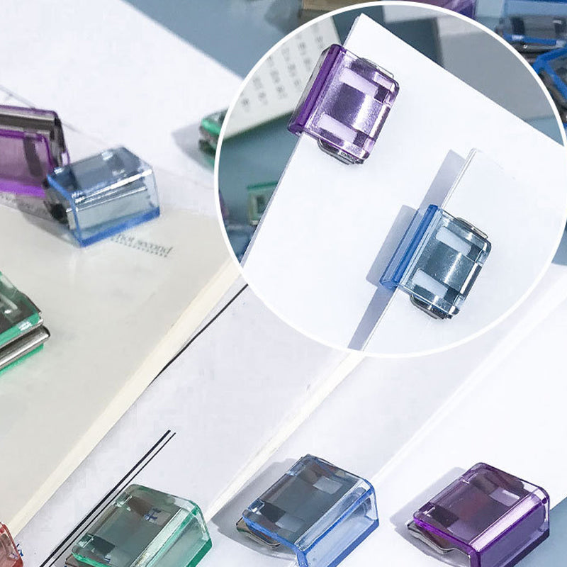 "Färgglada metallpappersklämmor i grönt, gult, lila, rosa, transparent och blått, perfekt för kontor och skola."