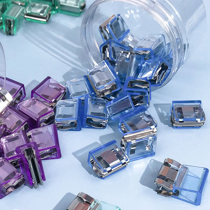 "Färgglada metallpappersklämmor i grönt, gult, lila, rosa, transparent och blått, perfekt för kontor och skola."