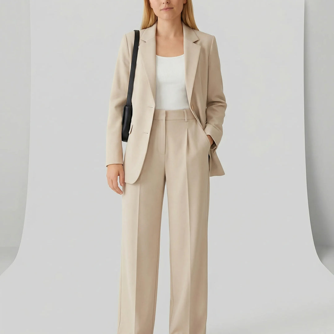 Stilren Zoe byxkostym i figursydd design. Professionell damkostym med kavaj och vida byxor för modern look.
