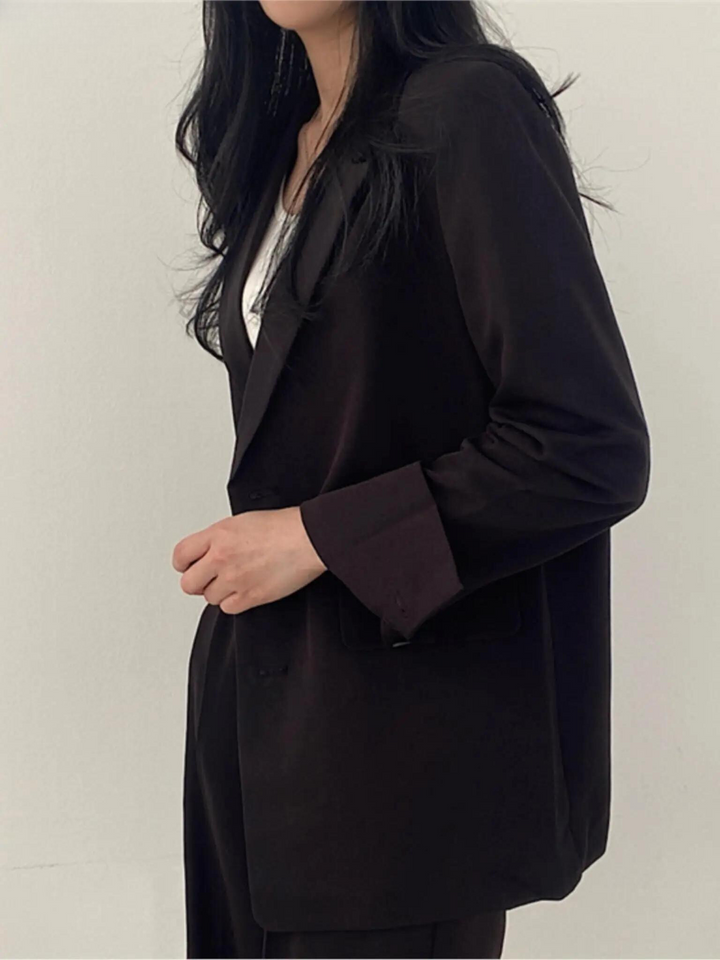 Beige figursydd damkostym, elegant blazer och vida byxor. Tidlös design för kontor och formella tillfällen.