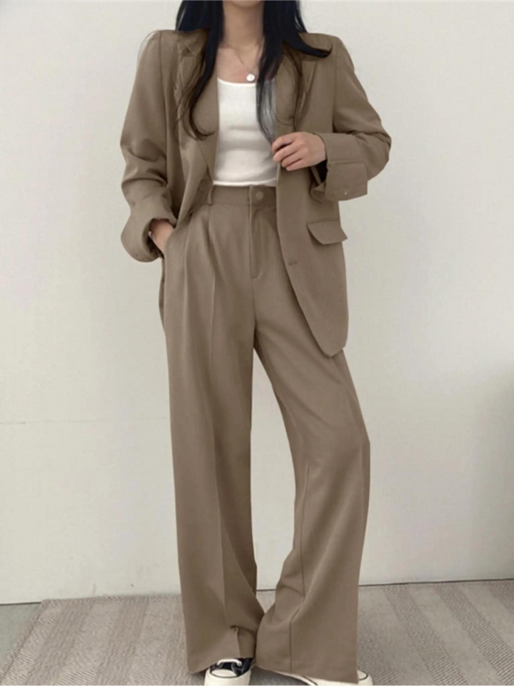 Skräddarsydd byxkostym för kvinnor med figursydd passform. Blazer och vida byxor för en modern look.