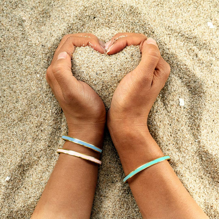 "Flerfärgat damarmband i robust stål med justerbar passform och livfulla orange, gula, blå, rosa, röda och svarta färger."