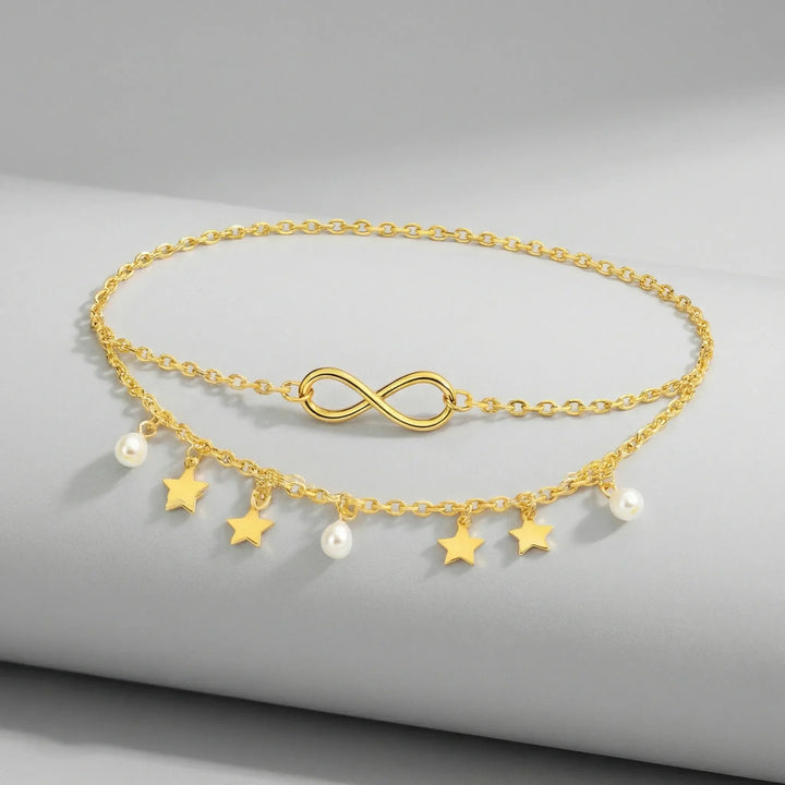 Elegant justerbar fotlänk för dam i guld & silver. Design med flätade kedjor, stjärnor och glänsande pärlor.
