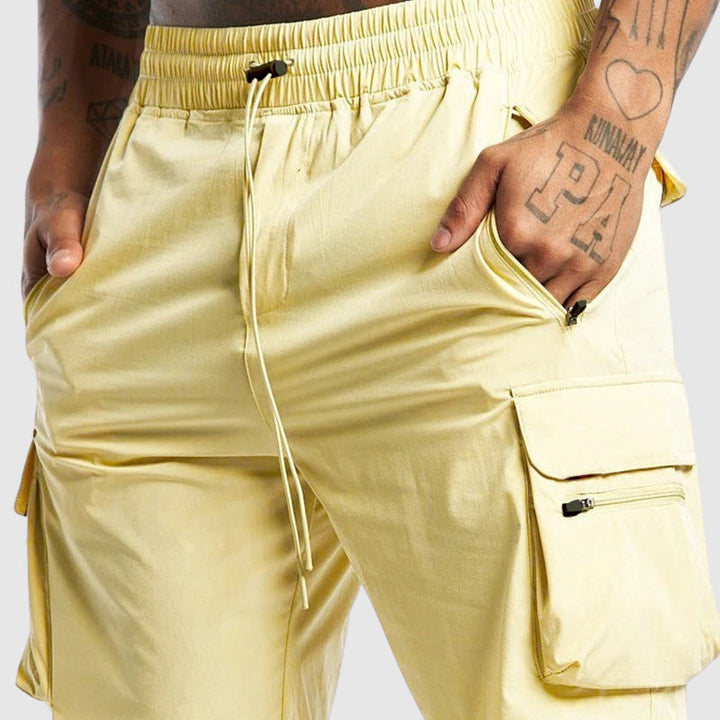 Närbild på tyg och sömmar hos svart herrshorts, framhäver kvalitet och lastfickor för bekvämlighet.