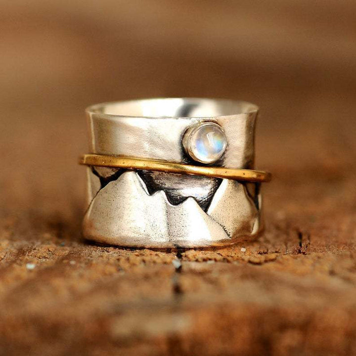"Guldfärgad damhjärtring med måne och berg, elegant accessoar med naturtema"