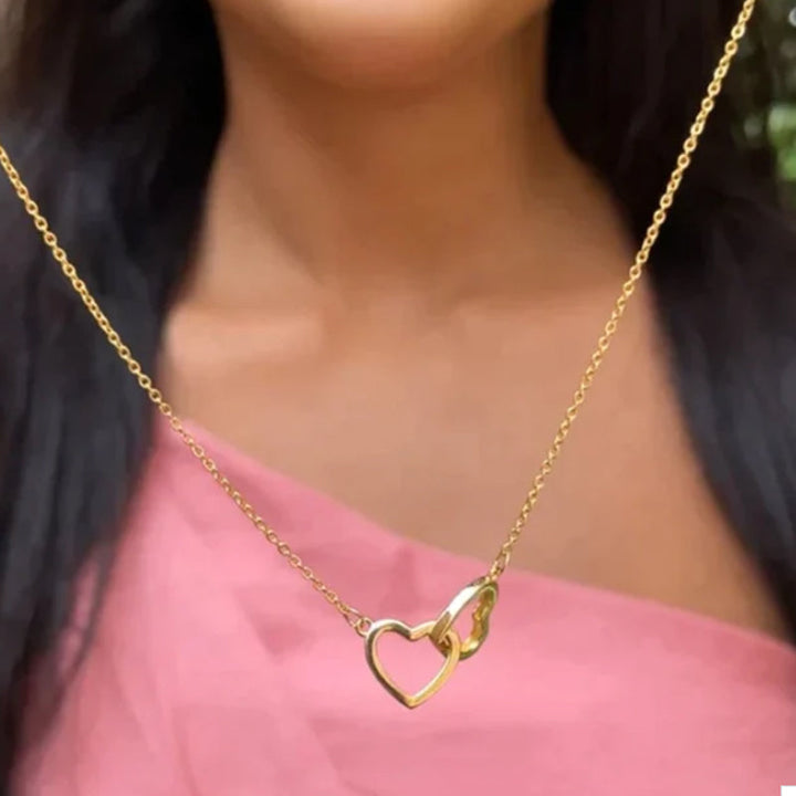 "Halsband för kvinnor med två sammanflätade hjärtan i titan stål, elegant romantisk design i guld, roséguld eller silver."