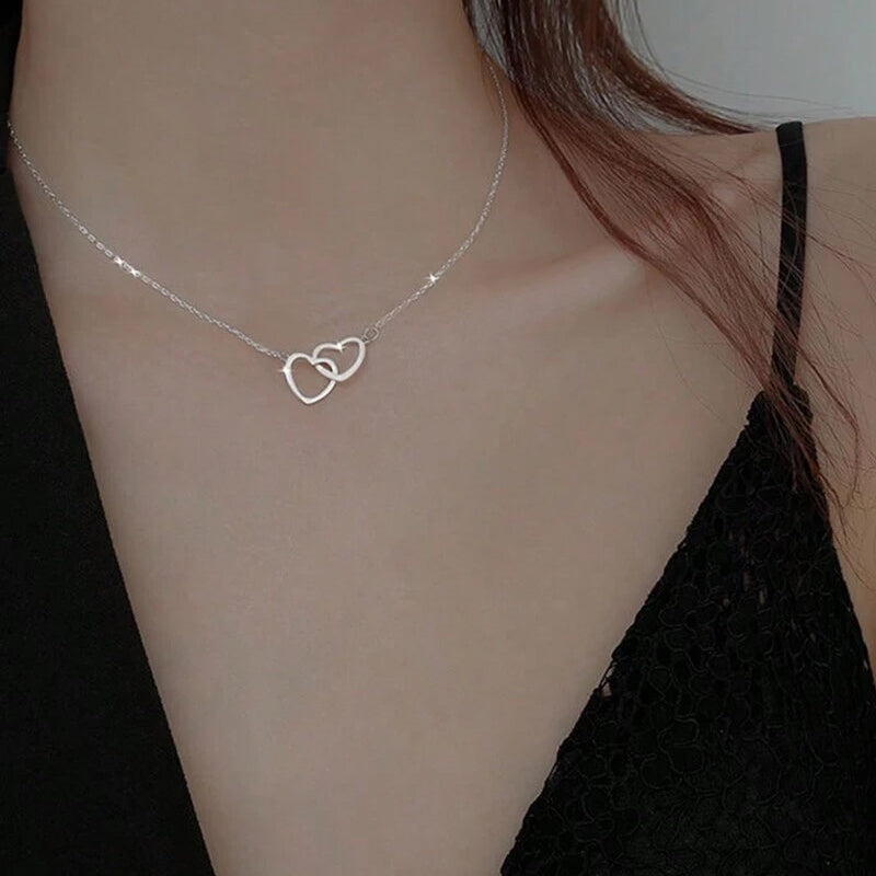 "Halsband för kvinnor med två sammanflätade hjärtan i titan stål, elegant romantisk design i guld, roséguld eller silver."