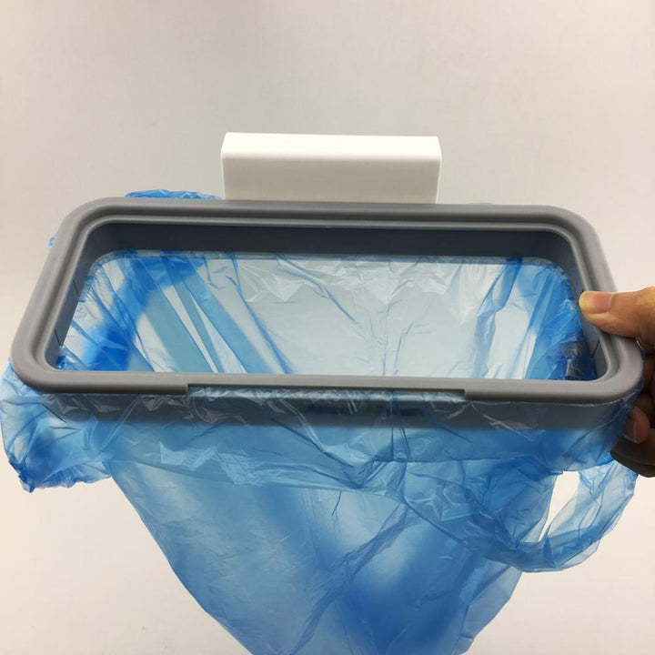 "Hängande papperskorgshållare i vit plast monterad på köksdörr, platsbesparande för smidig avfallshantering."