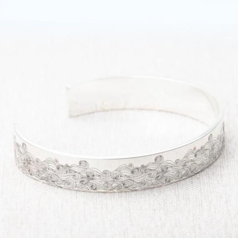 "Havsvåg justerbart armband i rostfritt stål på kvinnas handled, elegant vågdesign, perfekt accessoar för kvinnor."