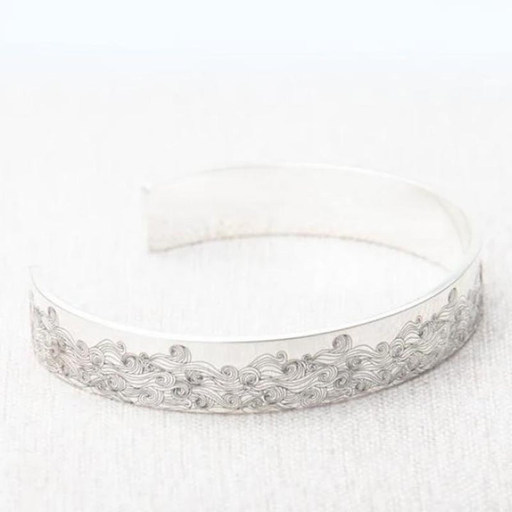 "Havsvåg justerbart armband i rostfritt stål på kvinnas handled, elegant vågdesign, perfekt accessoar för kvinnor."