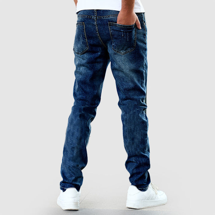 Studiobild av ett par blåa raka herrjeans, i en avslappnad passform, perfekta som helårsbyxor.