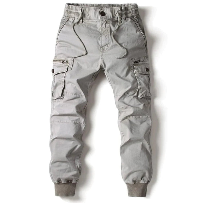 En stapel med vikta herrjoggers i olika färger, alla med lastfickor och elastisk midja.