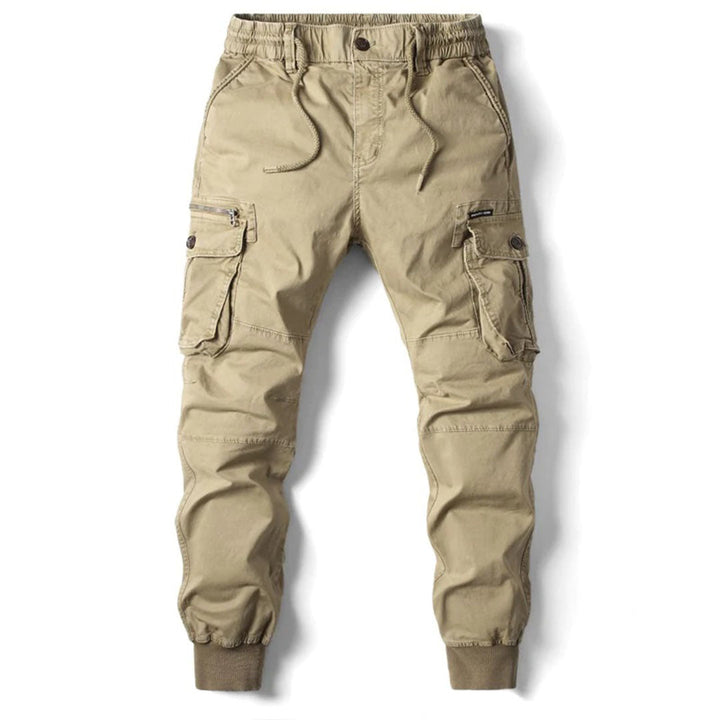 Närbild av tyget på herrjoggers, visar materialets struktur och en lastficka med knapp.