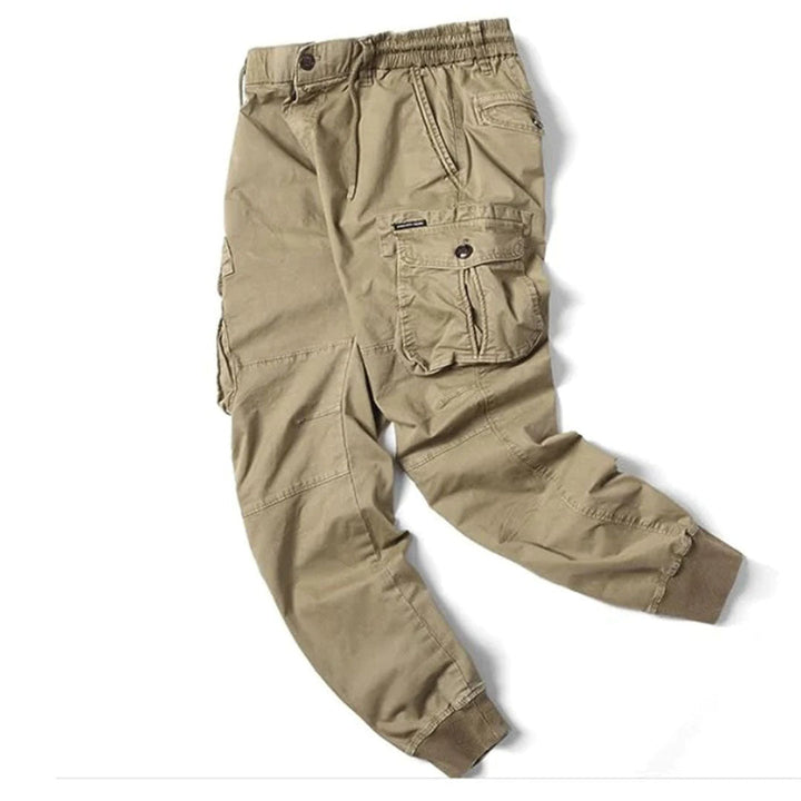 En man bär grå herrjoggers med elastisk midja och lastfickor, avslappnad stil för vardagsbruk.