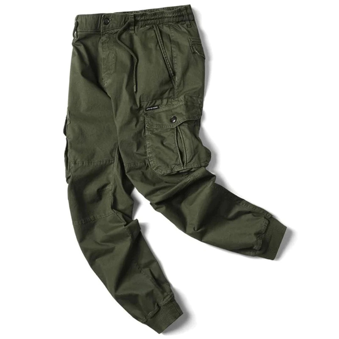 Modell som poserar i herrjoggers med lastfickor, visar byxorna från sidan, avslappnad look.