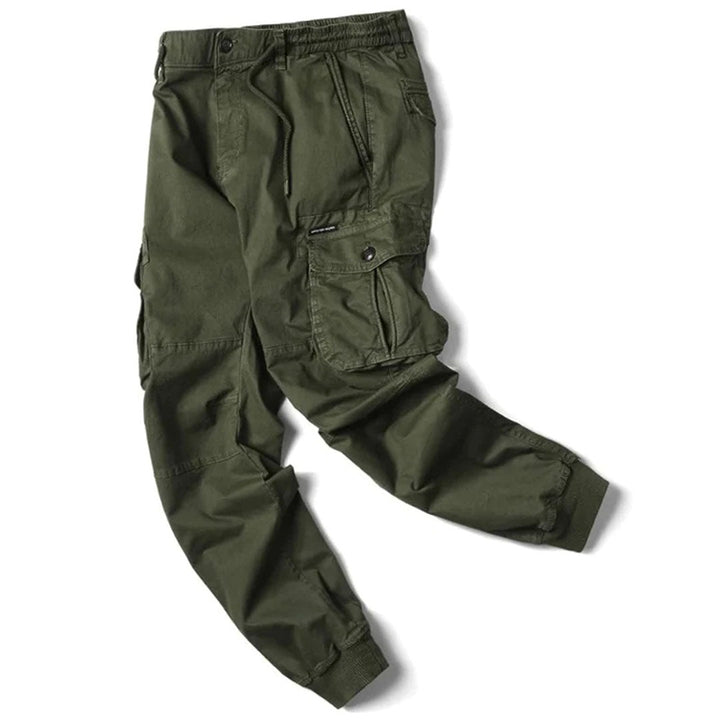 Modell som poserar i herrjoggers med lastfickor, visar byxorna från sidan, avslappnad look.