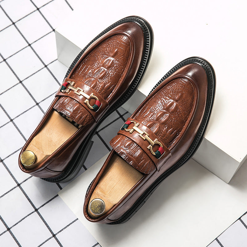 Närbild på präglad textur på herrloafers i läder med glänsande metallbit, en sofistikerad design.