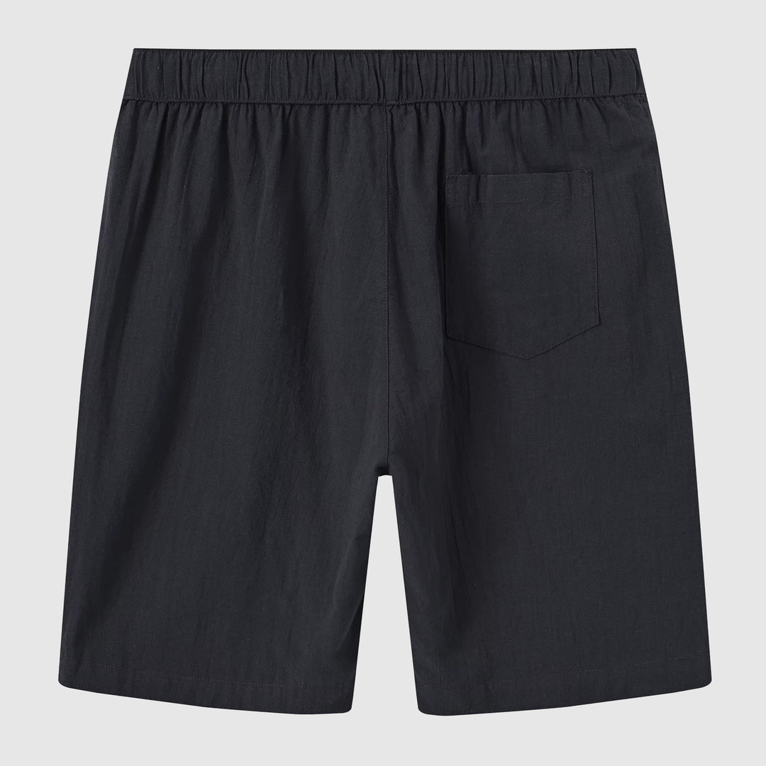 Modell visar blå linneshorts för män, bekväma och stilrena för sommarbruk.