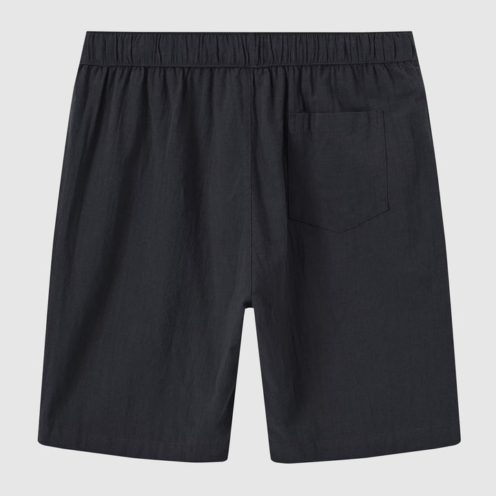 Modell visar blå linneshorts för män, bekväma och stilrena för sommarbruk.